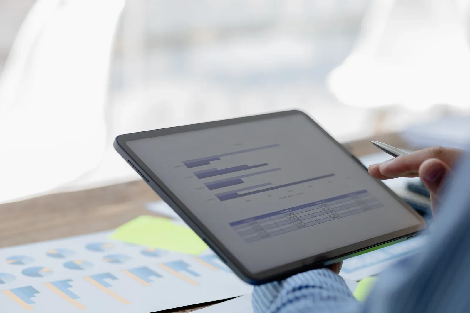 Person reading a report on a tablet over printed charts